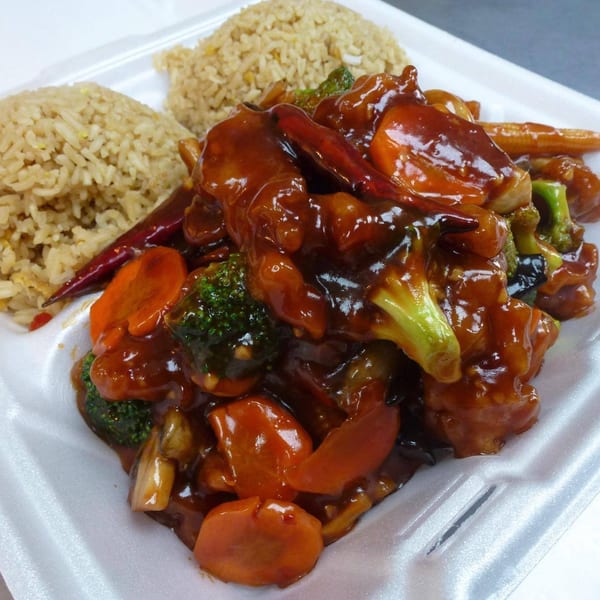 Three Happiness Express's Chinese dish with chicken, broccoli, carrots, and rice in a takeout container.
