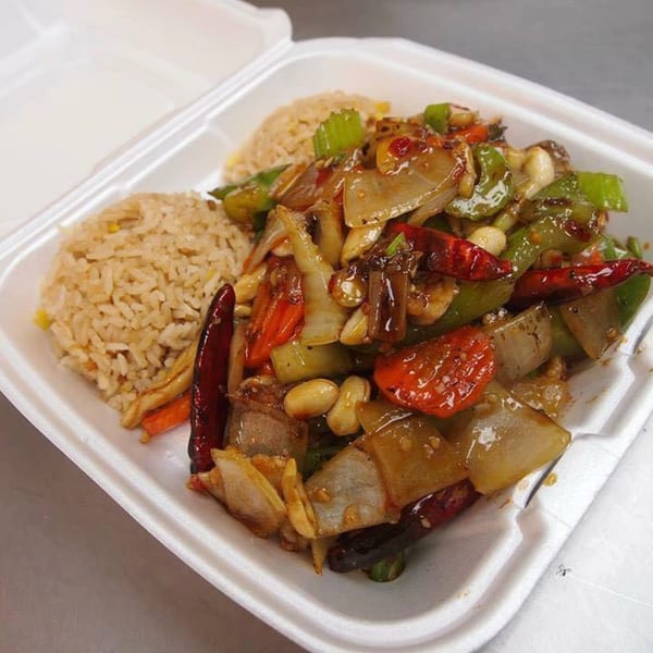 Kung Pao Chicken with fried rice in a white takeout container from Three Happiness Express.